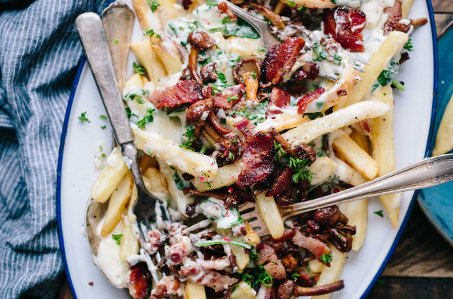 a plate filled with chips, meat, chives and creamy garlic sauce