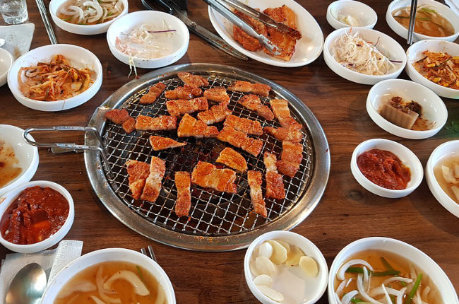 meat cooking in the middle of a table surrounded by food