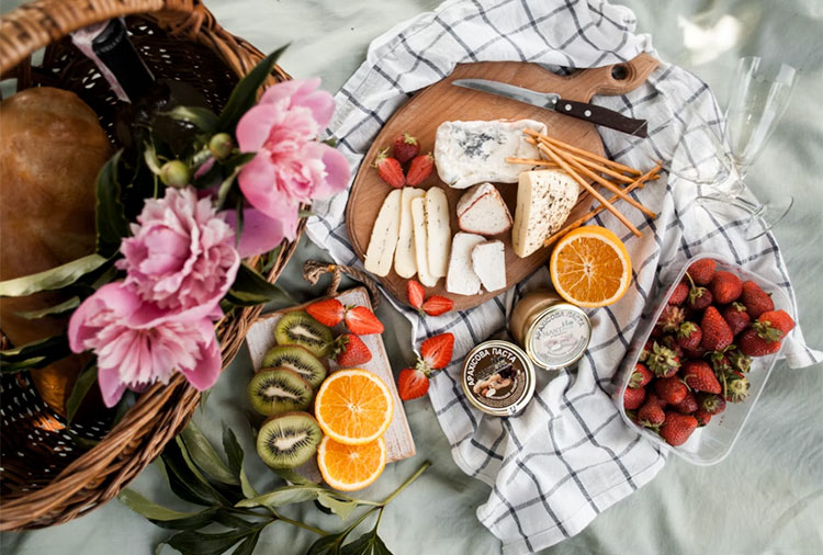 an array of fruits and cheese sliced up and placed on a chopping board