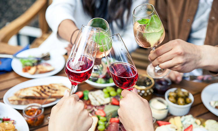 four people clanking their drinks together at a restaurant with a taps platter on the table