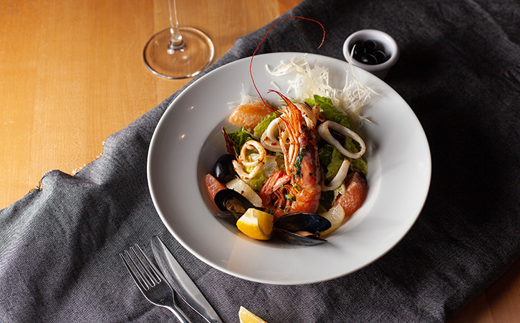 a seafood dish sitting on a table with a glass of wine