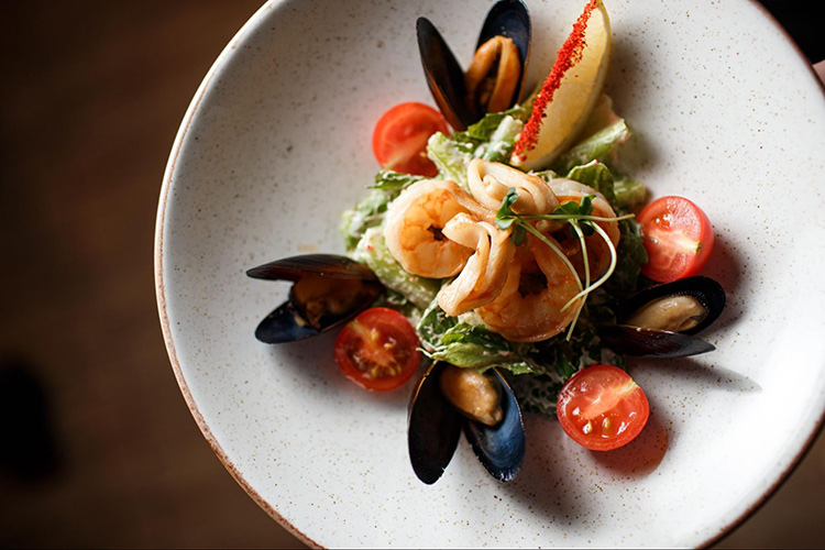 White plate with prawns, mussels and garnishes 